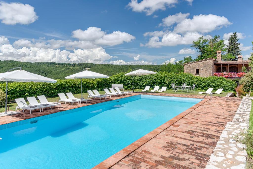 a swimming pool with chairs and umbrellas at Tenuta Acquabona - intero casale in Gambassi Terme