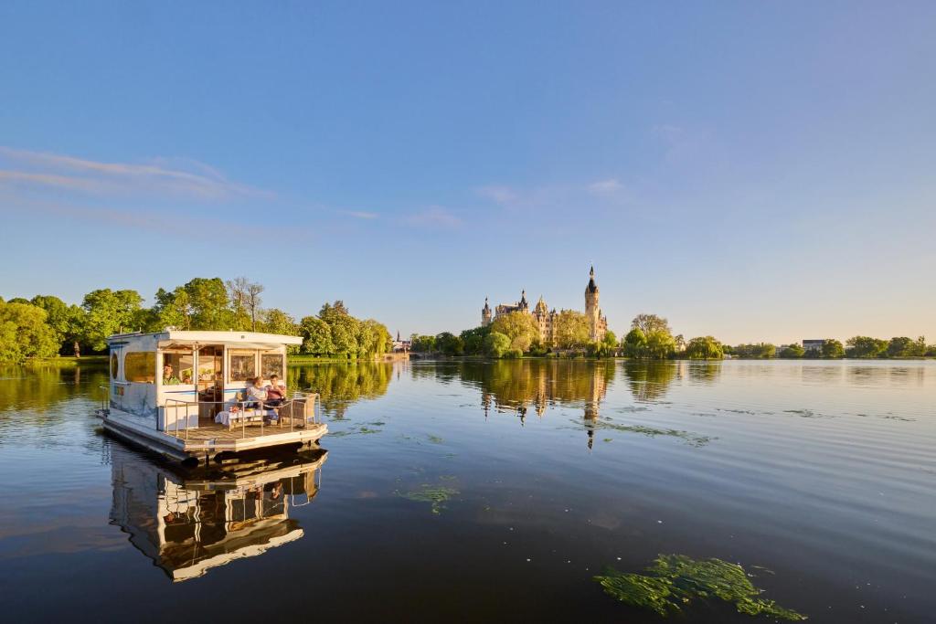 a boat on a lake with a castle in the background at Hausboot Saturn in Schwerin