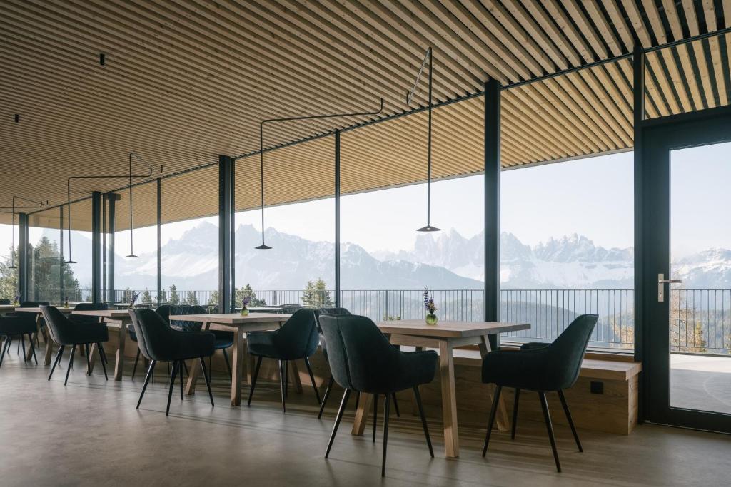 a dining room with tables and chairs and a large window at anders mountain suites 4 in Brixen