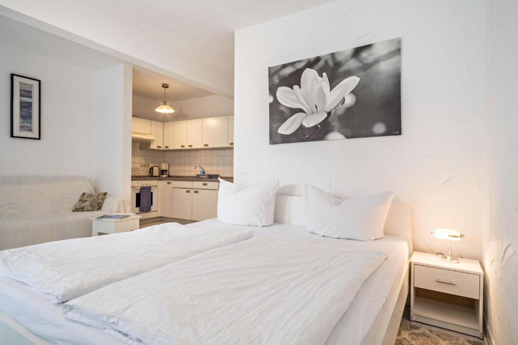 a white bedroom with a white bed and a kitchen at Fewo Eg Rechts - Hunde erlaubt in Oberteuringen