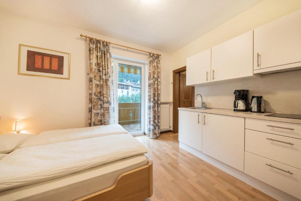 a bedroom with a large bed and a kitchen at Residence Kronstein - Fewo 4 in Tesimo