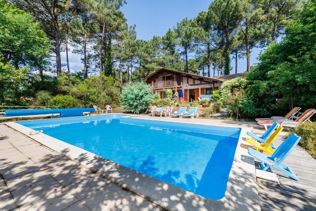 a swimming pool with chairs and a house at Maison entre Lac et Océan in Biscarrosse