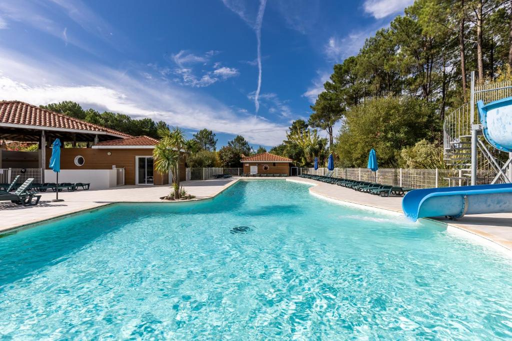 a large swimming pool with a slide in a house at Chalet Climatisé Biscarrosse in Parentis-en-Born