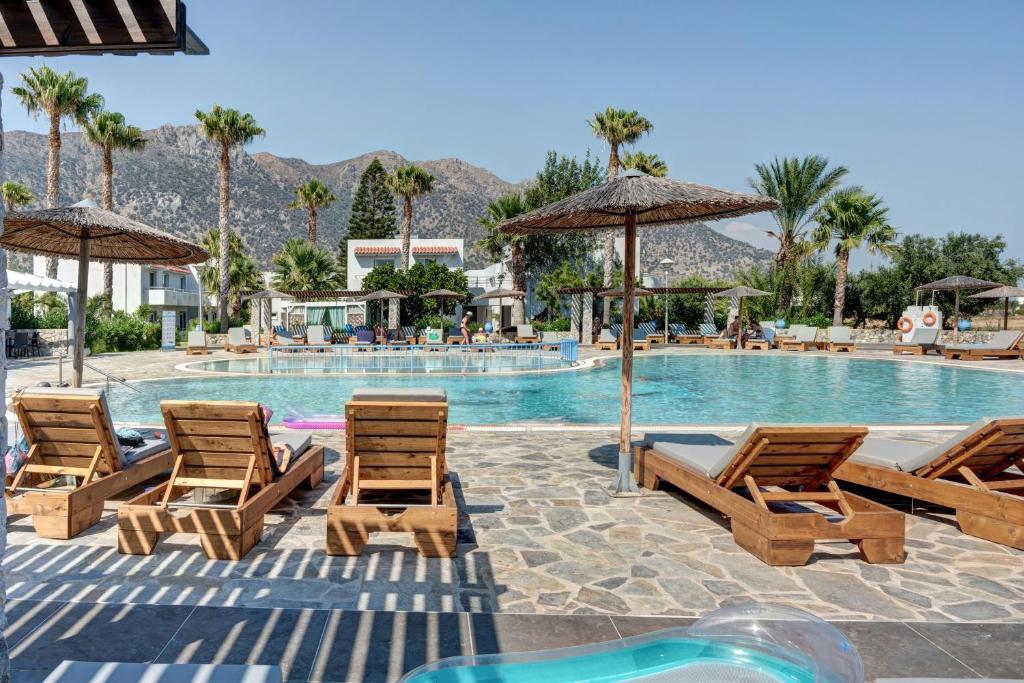 a group of chairs and umbrellas next to a swimming pool at Evripides family one -bedroom 1 in Kardamaina