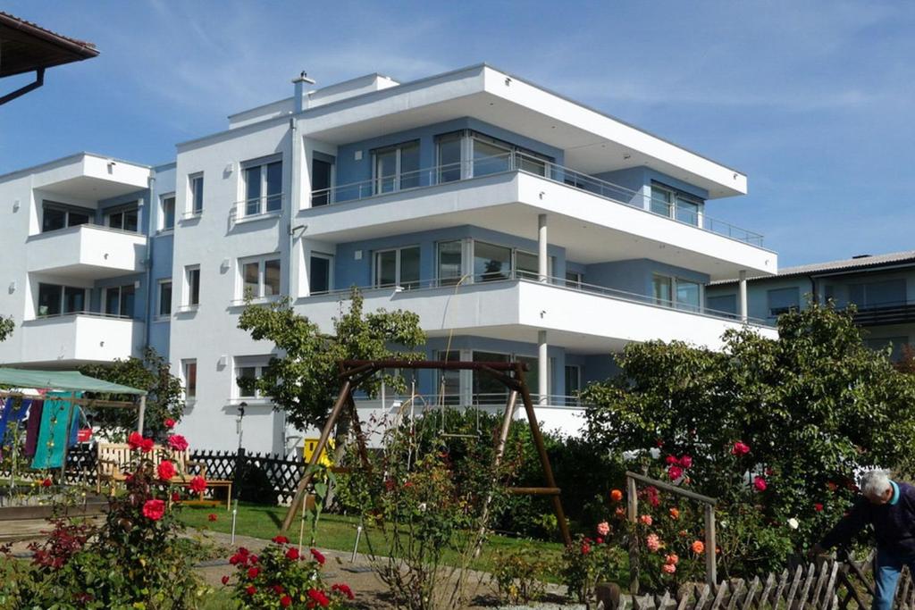 a large white building with a garden in front of it at Appartements Bank Am See in Immenstaad am Bodensee