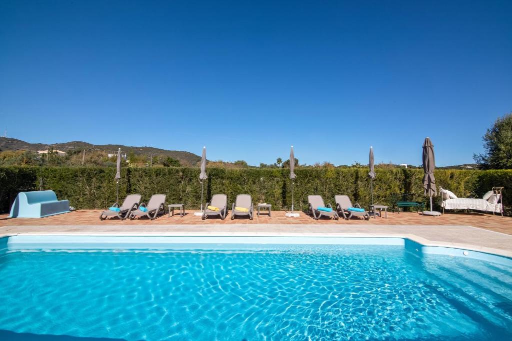 a swimming pool with chaise lounges and chairs around it at Villa Oliva Al in Moncarapacho
