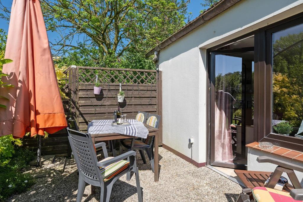 a patio with a table and chairs and an umbrella at An der Silberfuchsbörse in Wurster Nordseeküste