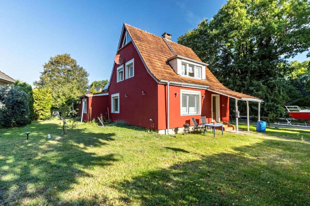 a red house on a grassy yard with trees at Ferienwohnung Jesteburg in Jesteburg