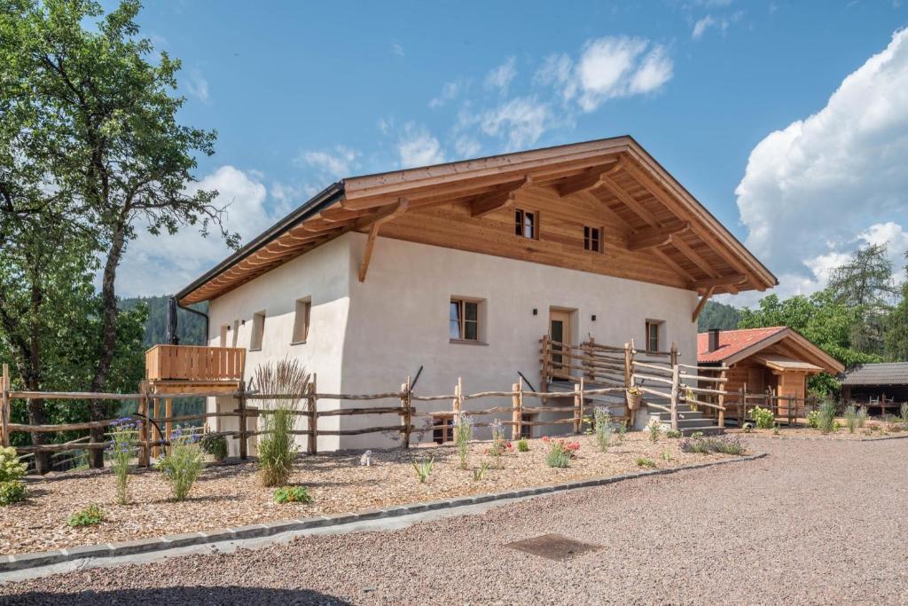 a house with a wooden roof and a fence at Egger an der Lahn - Apt Dolomiten in San Genesio Atesino