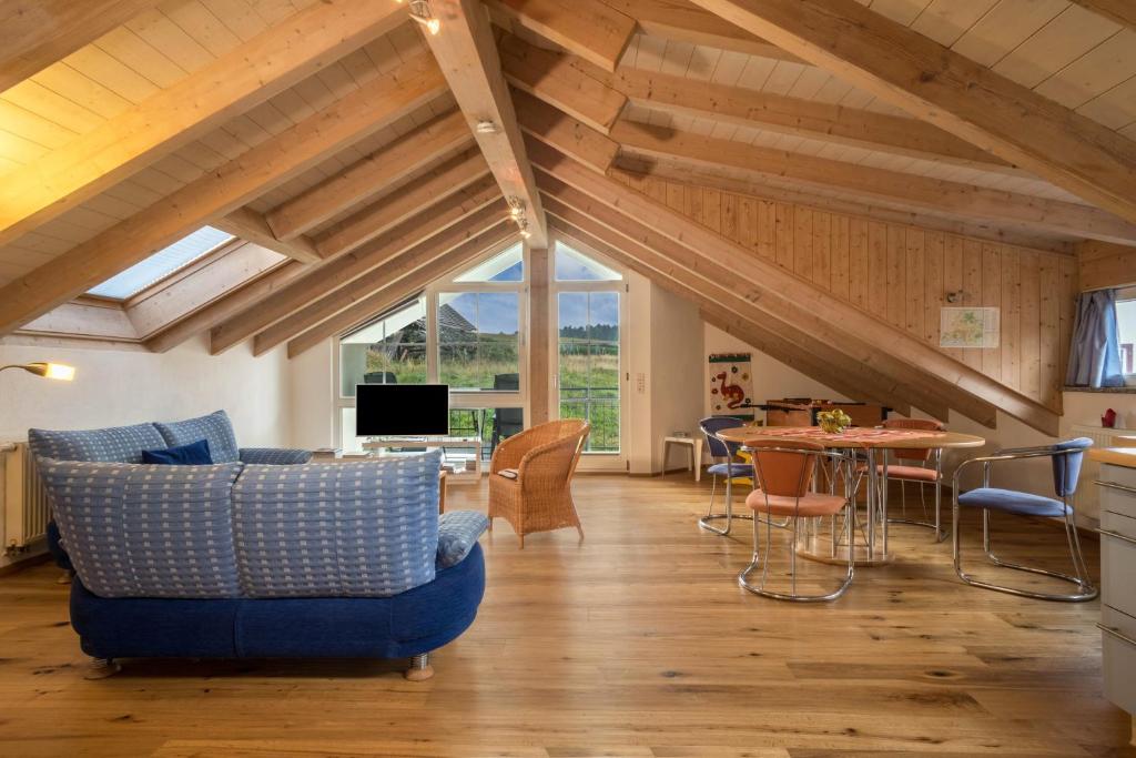 a living room with a blue couch and a table at Ferienwohnung Schleinseeblick in Kressbronn am Bodensee