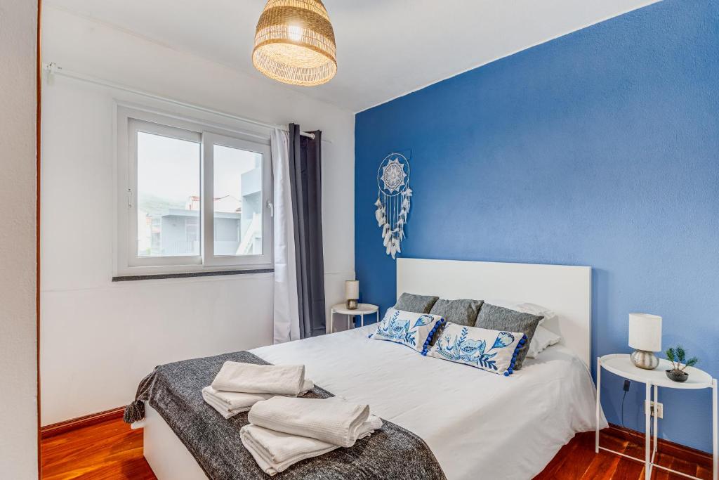 a blue and white bedroom with a bed and a window at Casa da Travessa com 3 Quartos in Horta