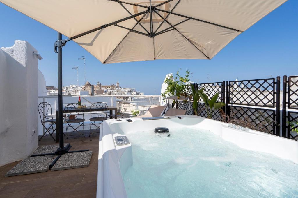 a hot tub on a balcony with an umbrella at Suite Cavour 30 in Ostuni