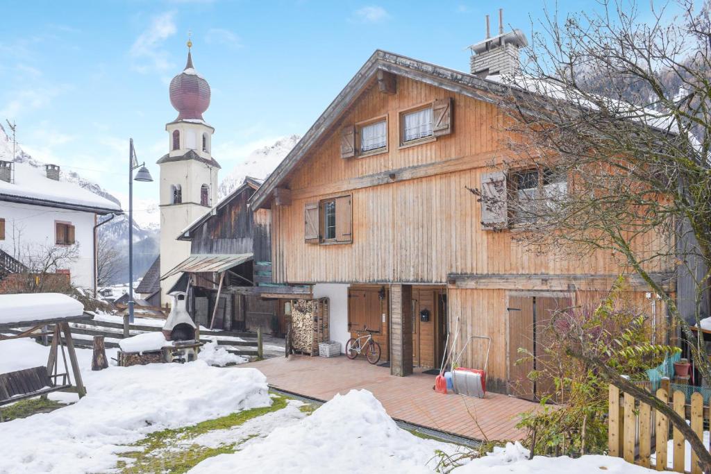 a wooden house with a church in the snow at Villetta Crepaz in Canazei