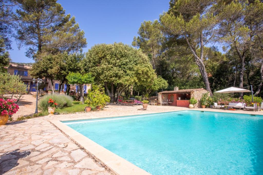 a large swimming pool in a yard with trees at Bastide Lou Pèbre D’aï in La Roquebrussanne