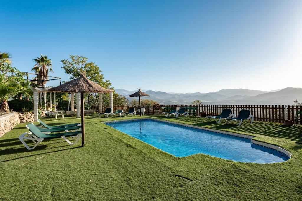 a swimming pool in a yard with a chair and umbrella at Casa Rural Salrima in Alora