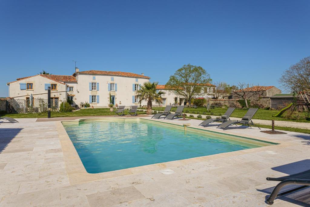 a swimming pool with chairs in front of a house at La Belle Parenthèse à la Rochelle in Vergné
