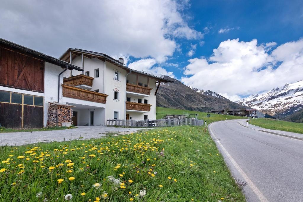 a house on the side of a road with flowers at New Teindlhof in Curon Venosta