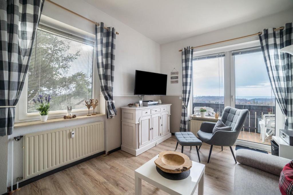 a living room with a couch and a tv and windows at Harzperle Wohnung Nr 6 in Braunlage