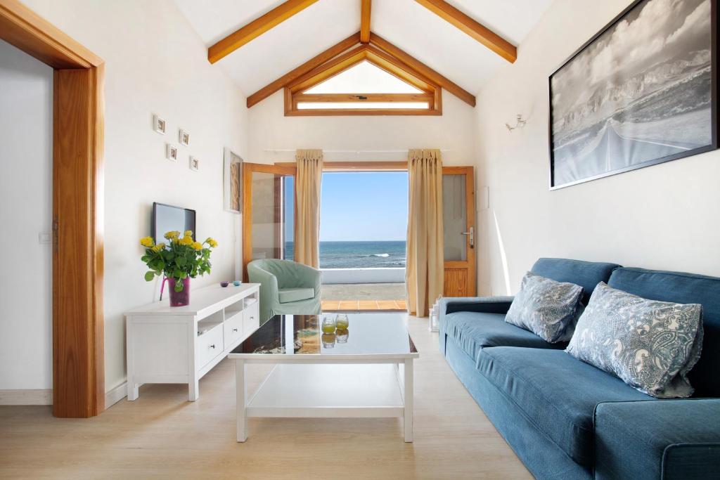 a living room with a blue couch and a view of the ocean at Casita Martina in Punta Mujeres