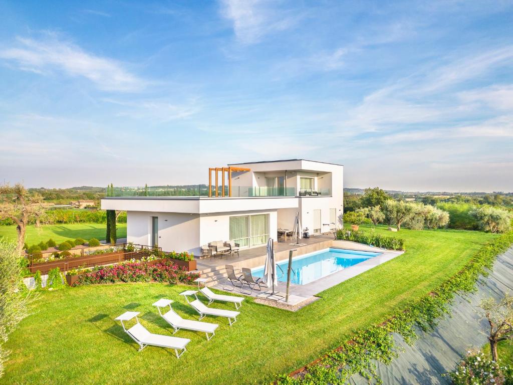 a house with a swimming pool and lounge chairs at Villa Angelina in Lazise