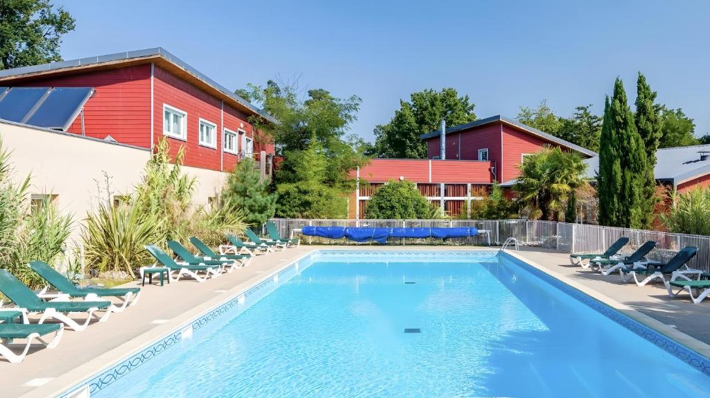 a swimming pool with lounge chairs and a house at Appartement paisible Richelieu in Chaveignes