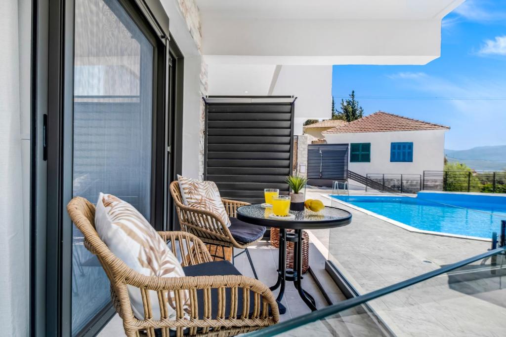 a balcony with a table and chairs and a pool at Oceanida Thalia Lyxury Suite in Nikiana