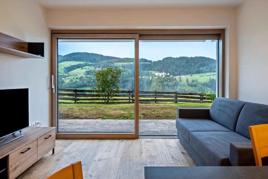 a living room with a couch and a large window at Appartement Schlern Living 1 in Völs am Schlern