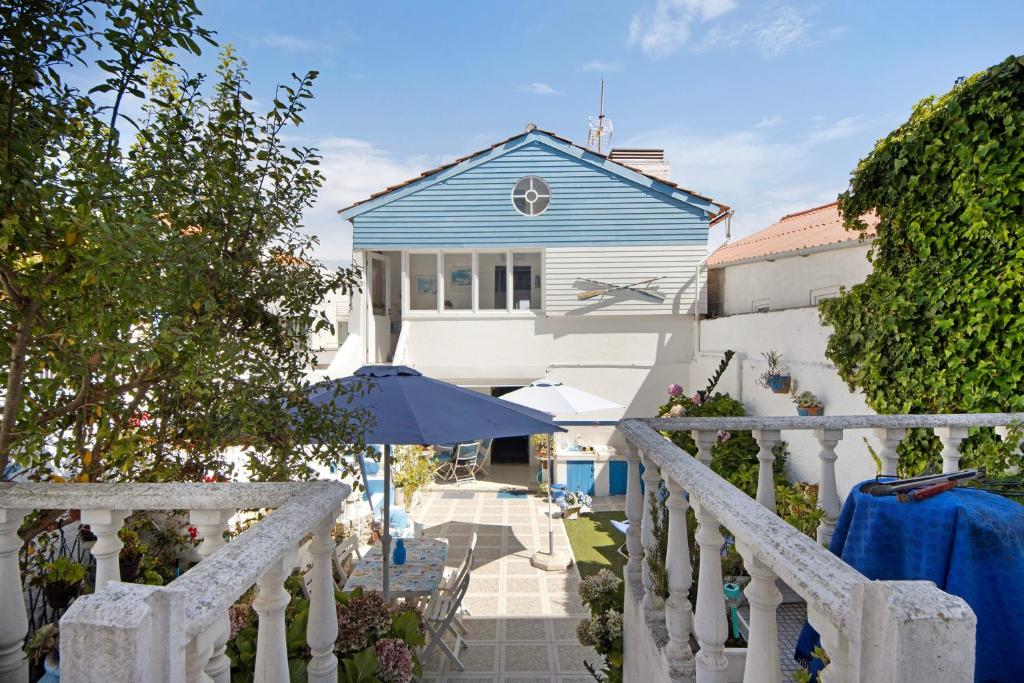 a blue and white house with an umbrella at Casa dos Afectos - Costa Nova in Gafanha da Encarnação