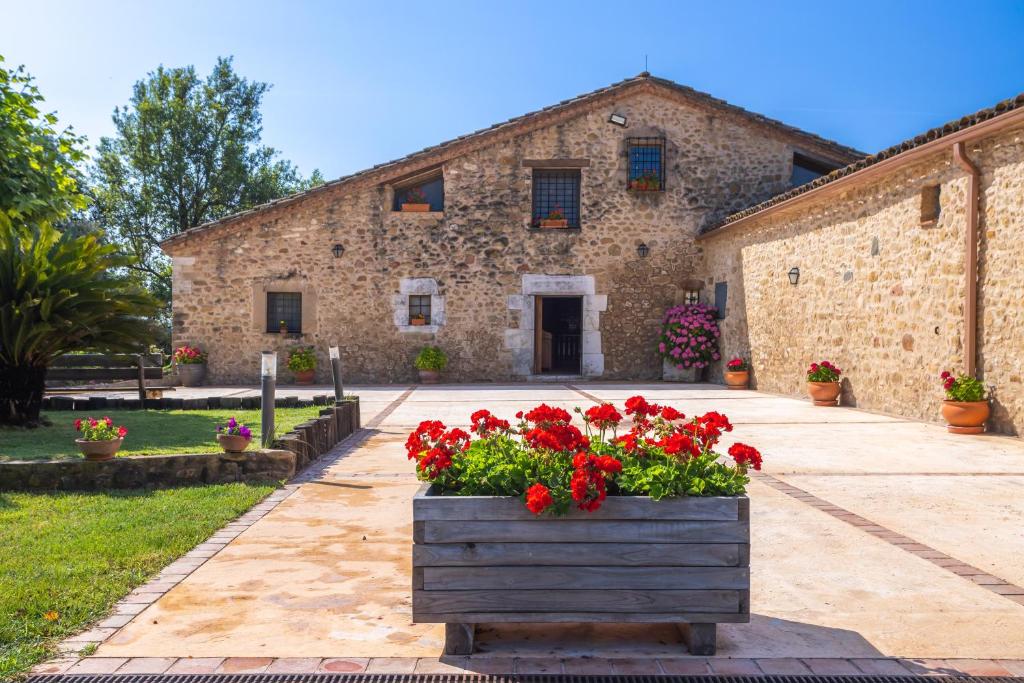 a stone building with a flower box of red flowers at Can Mas in Fontcuberta
