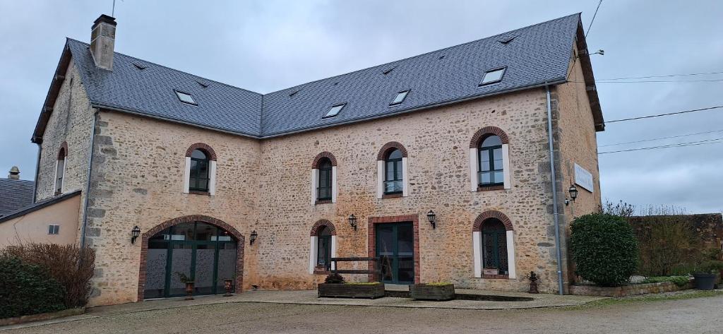 a large brick building with a black roof at Domaine de Meslay in Fyé