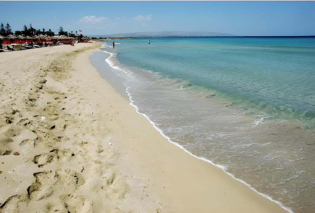 a beach with the ocean and people in the water at L' oro dei Magi San Lorenzo in Reitani