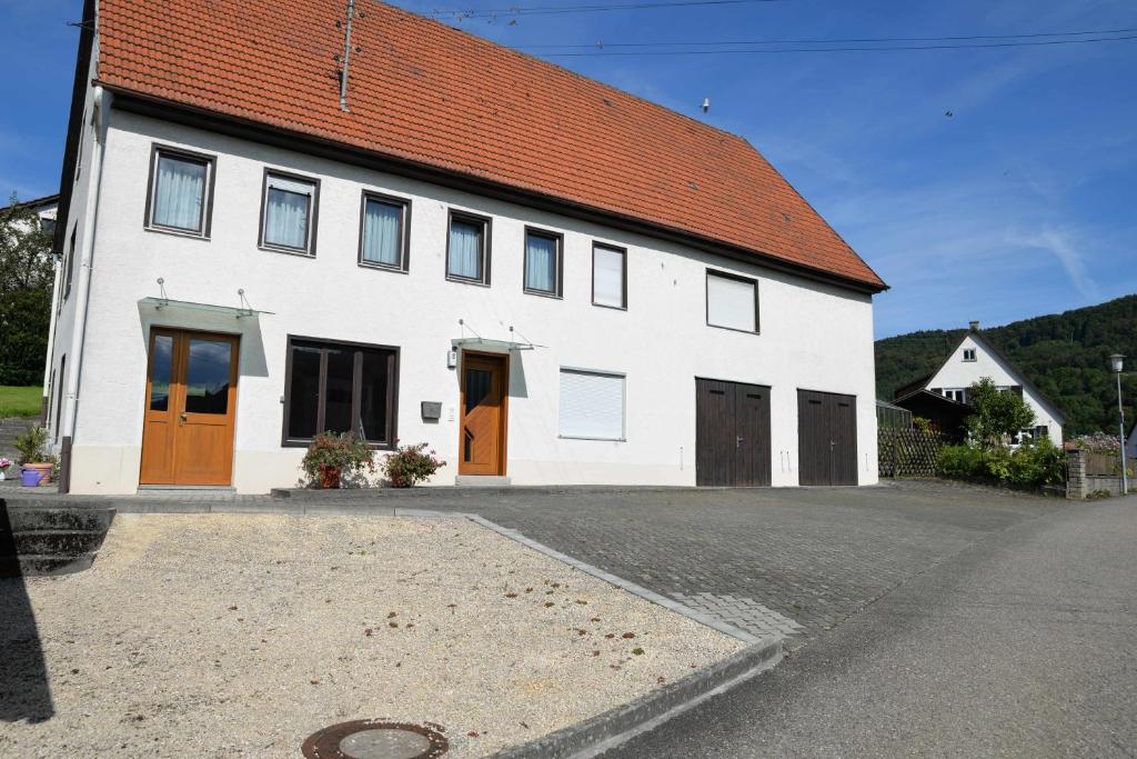 a white house with orange doors and a street at Ferienwohnung Dürnbach in Albstadt
