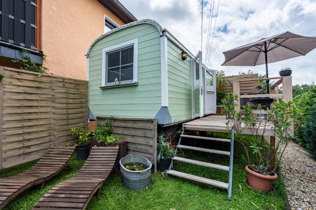 a green tiny house with stairs and an umbrella at Amselnest in Dobeneck