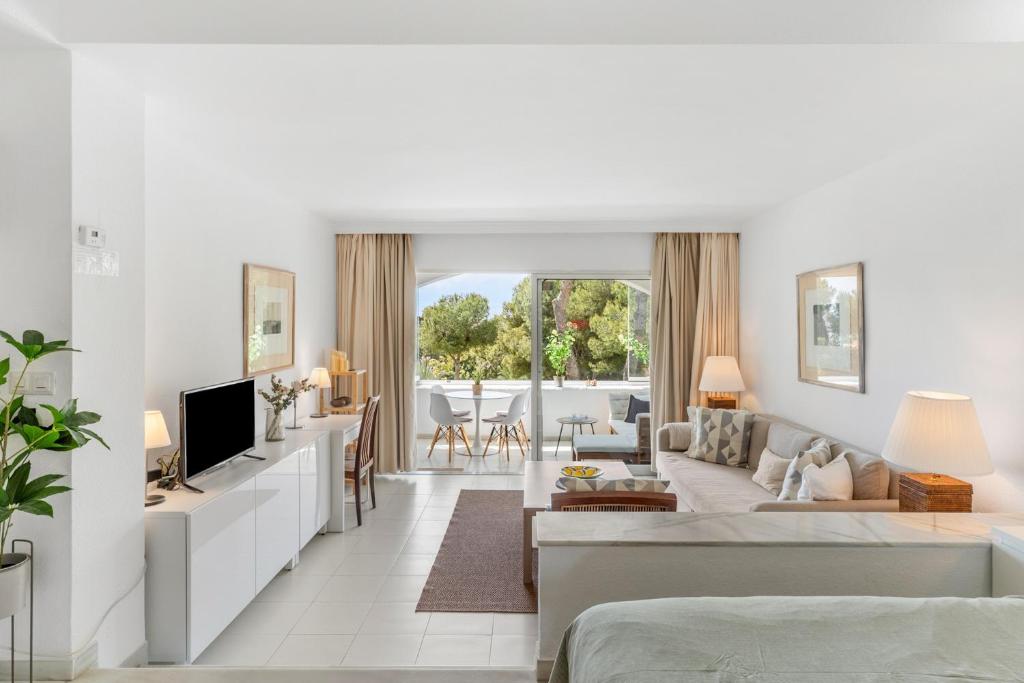 a white living room with a couch and a tv at Miraflores A112 in La Cala de Mijas