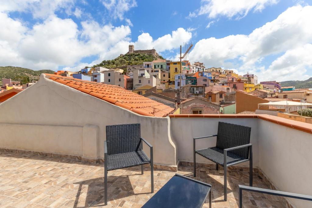 two chairs sitting on top of a roof with a city at Casa Rocca in Bosa