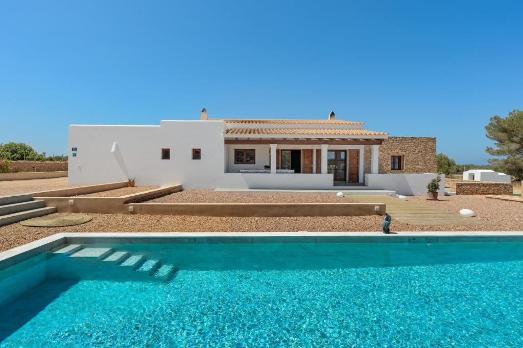 a villa with a swimming pool in front of a house at Casa S'Olibassa in La Mola