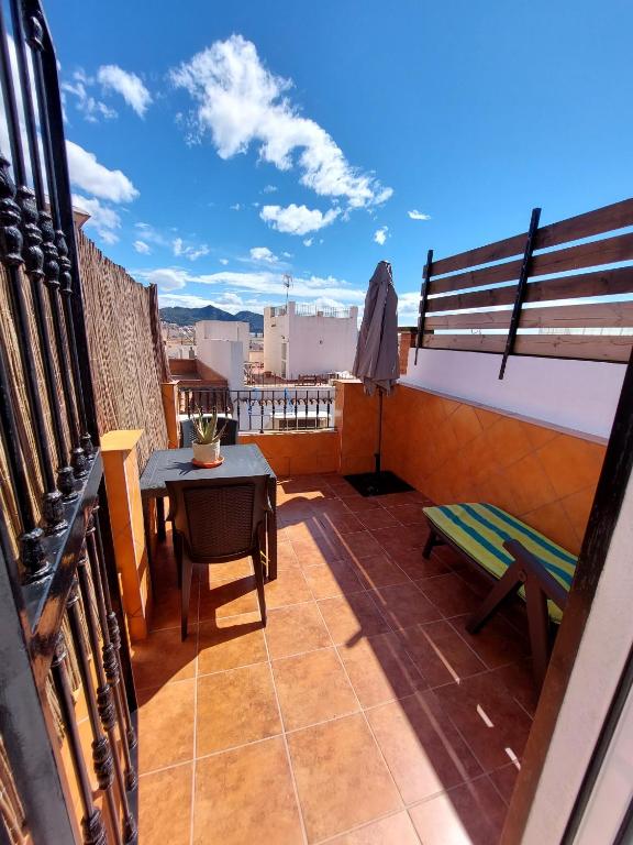 a balcony with a table and a bench on a roof at Estudio lola in Nerja