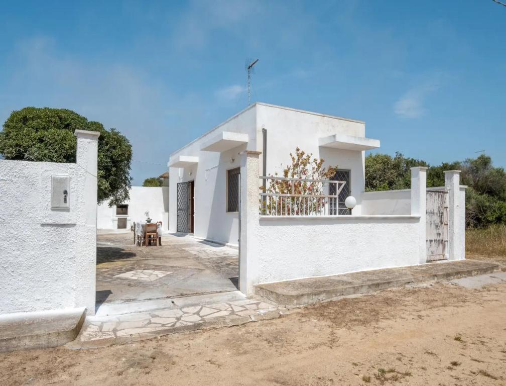 a white house with a gate in front of it at Villa del Mirto Punta Prosciutto in Torre Lapillo