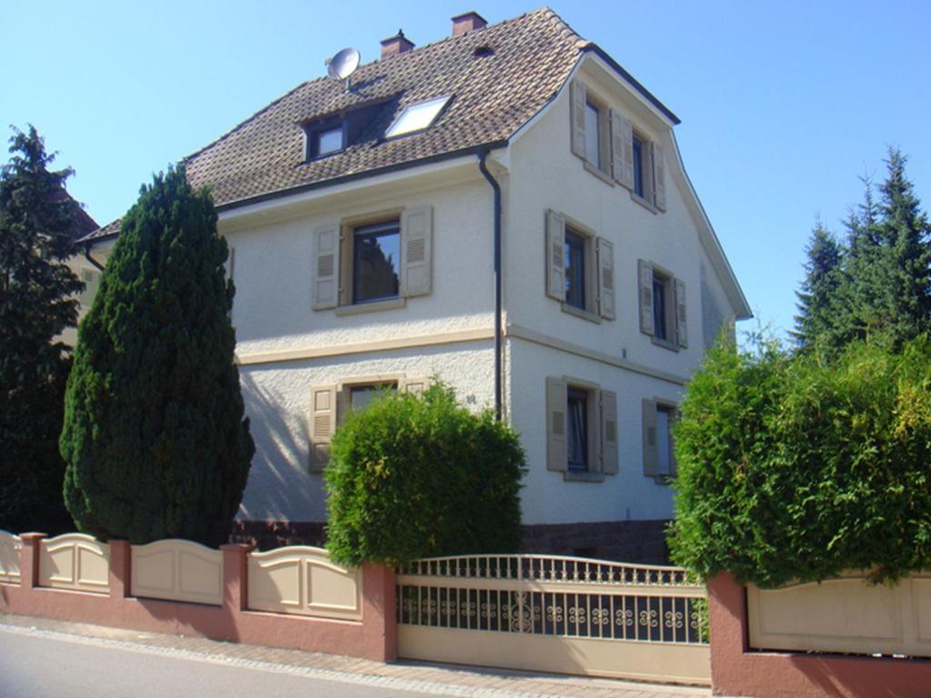 a white house with a fence and trees at Ferienwohnung Sprang in Steinen