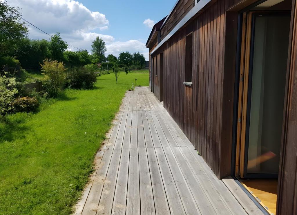 a wooden walkway next to a building with a yard at Au P'tit Venton - Maison Écologique in La Jaille-Yvon