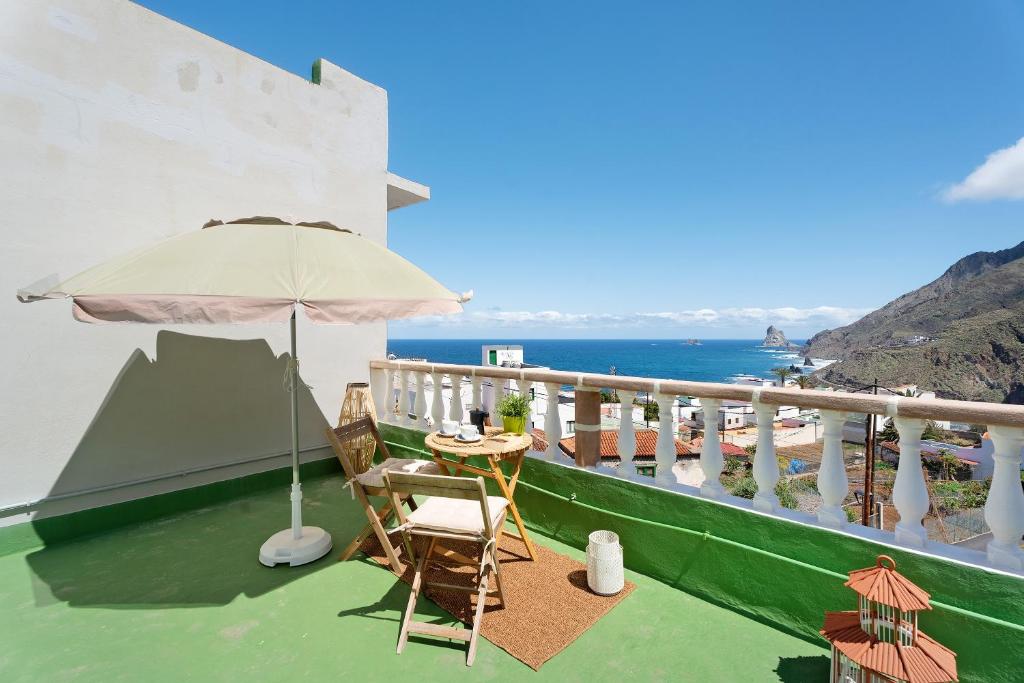 a balcony with a table and an umbrella at House in Anaga in Almáciga