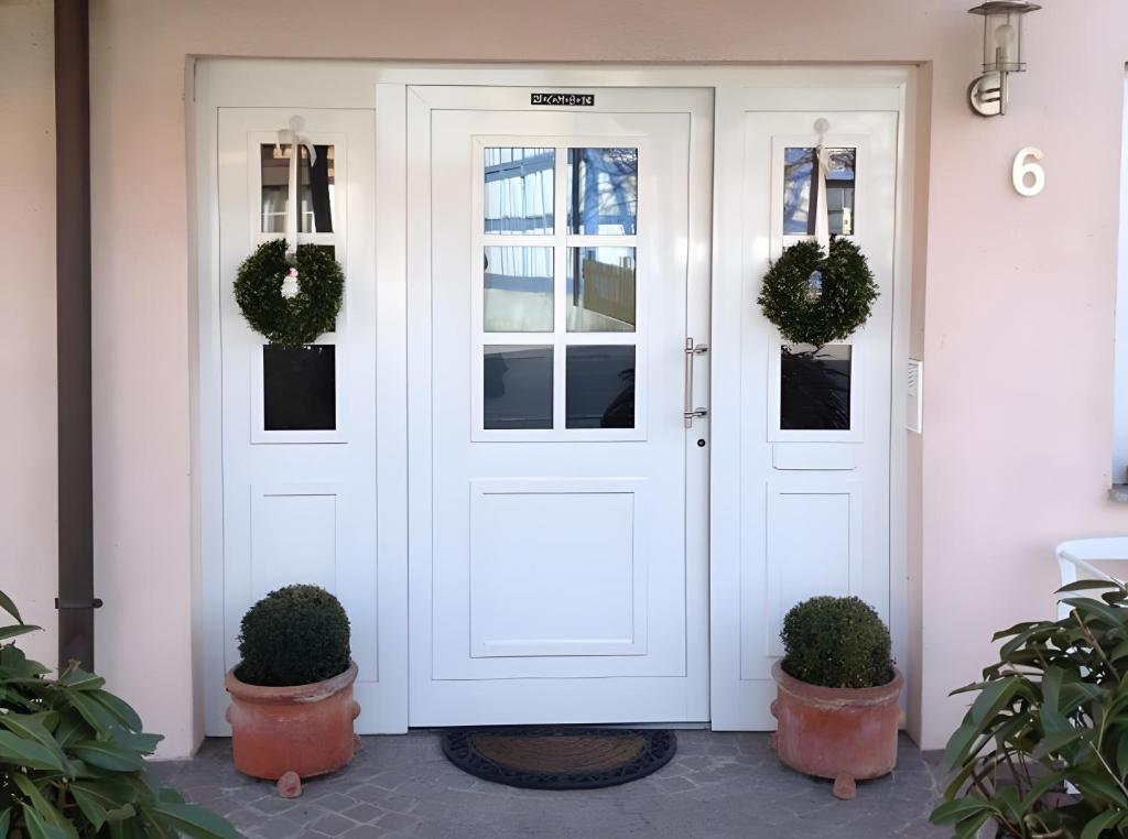 a white front door with two potted plants at Privatzimmer Kippenhausen in Immenstaad am Bodensee