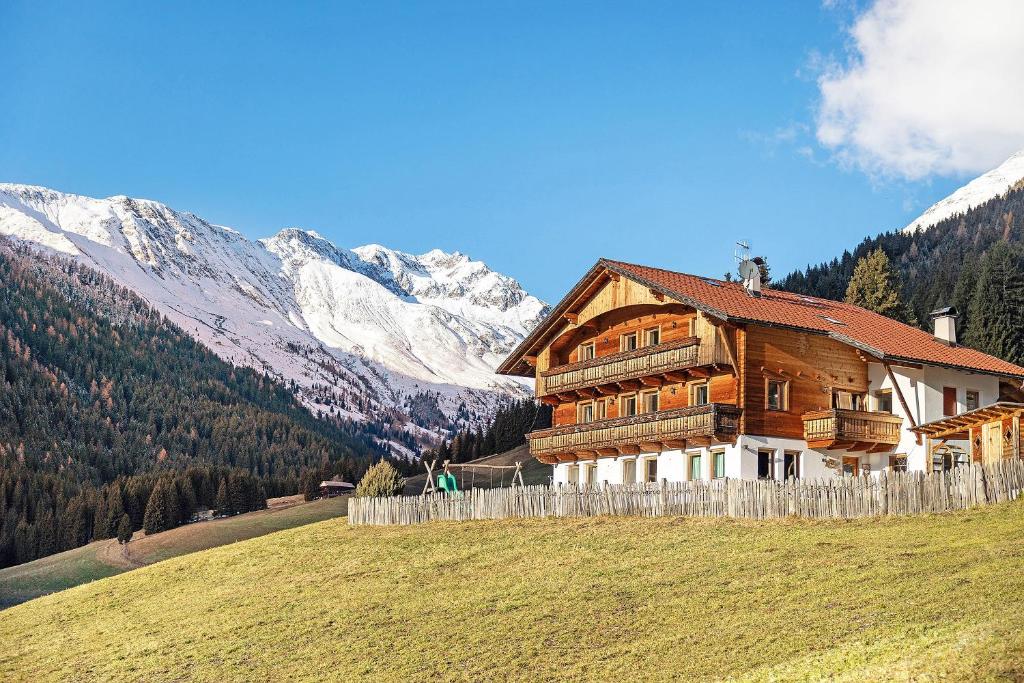 a wooden house on a hill with mountains in the background at Burgerhof in Gsies