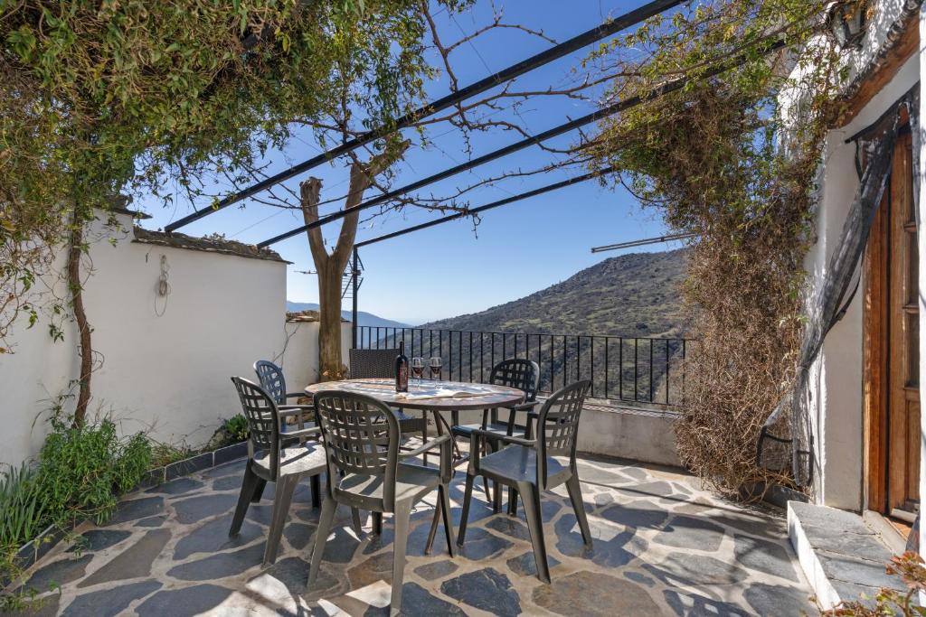 a table and chairs on a patio with a view at Casa de la Fuente in Bubión