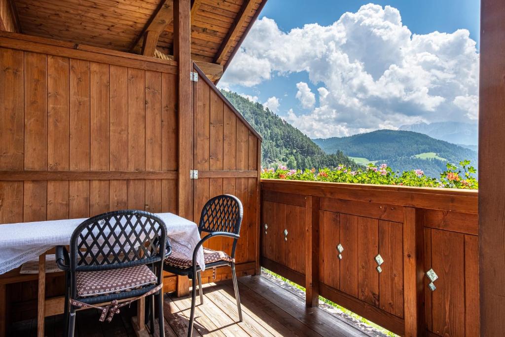 a balcony with a table and two chairs and a view at Gamperhof Apartment Planet in Collepietra