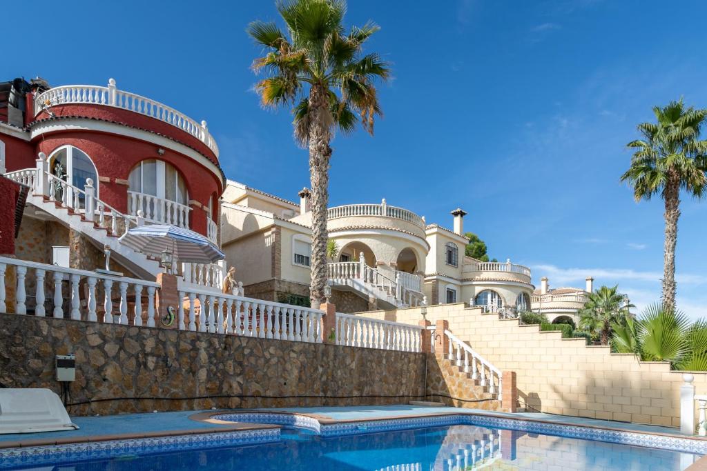 a house with a swimming pool and palm trees at Rr Villa in Monforte del Cid