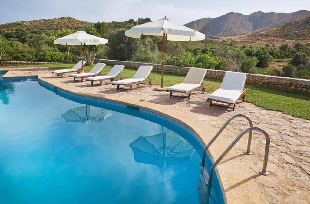 a group of chairs and umbrellas next to a swimming pool at Sa Mesquida de D’alt in Capdepera