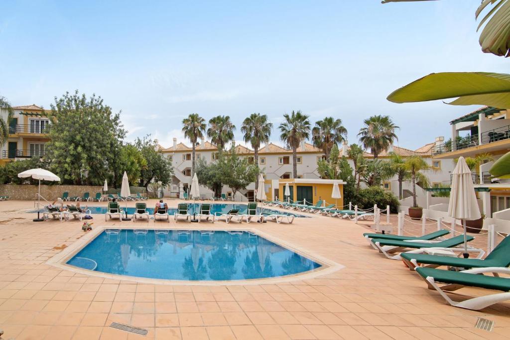 a large swimming pool with lounge chairs and umbrellas at Apartamento Tavirasol in Tavira