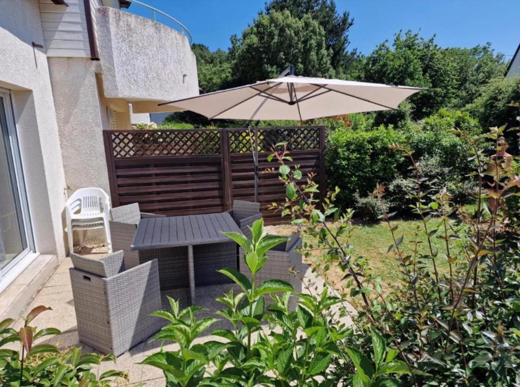 a patio with a table and an umbrella at La Mouette St Philibert 3 étoiles in Saint-Philibert