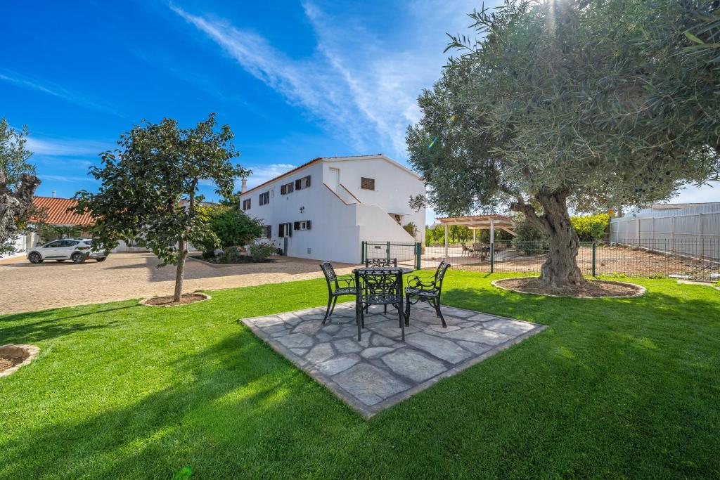 a table and chairs in a yard with a tree at Orange Blossom Grove in São Bartolomeu de Messines